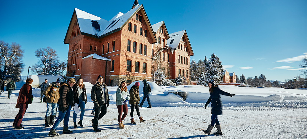 Tour walks past Montana hall on a beautiful sunny morning.