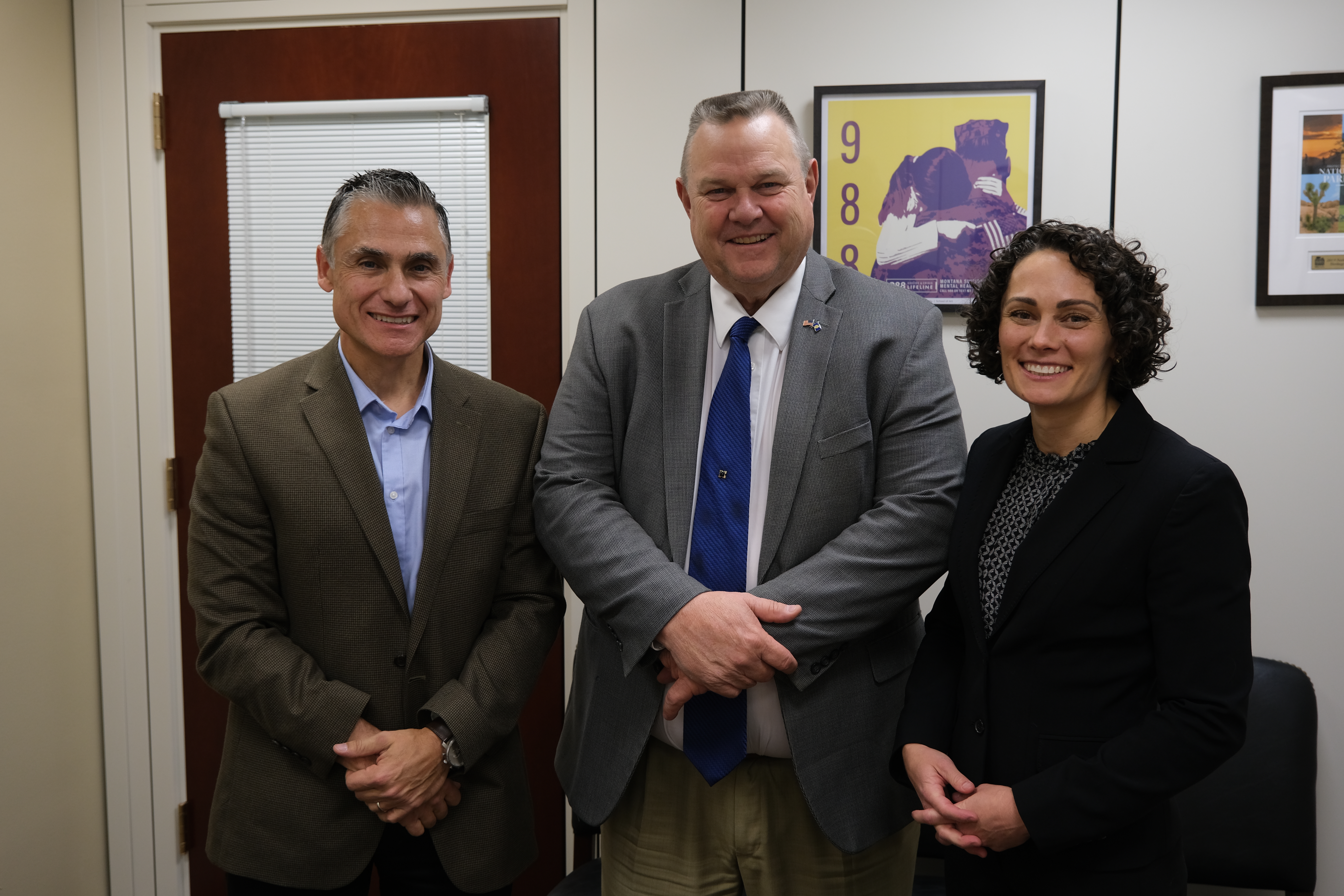 Two men and one woman standing next to each other in an office