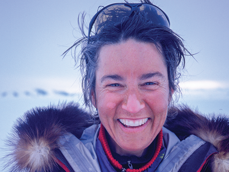 A person with a red jacket and glasses on the top of their head smiling at the camera