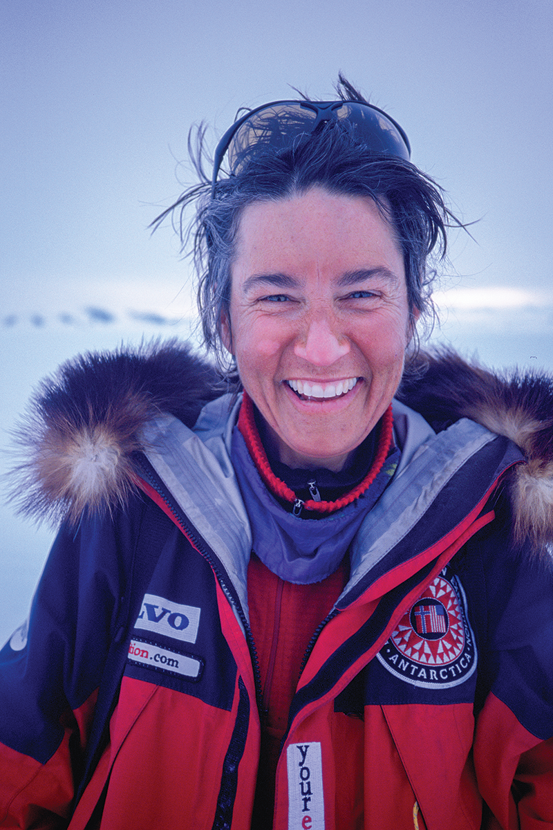 A person with a red jacket and glasses on the top of their head smiling at the camera