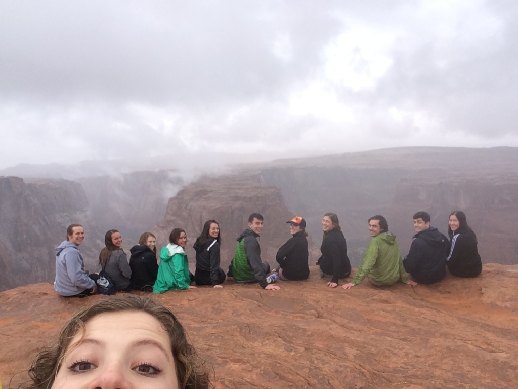 Students sitting along the edge of a canyon in a row