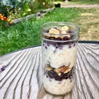 An image of a make ahead breakfast parfait on a wooden table in a yard with green grass.