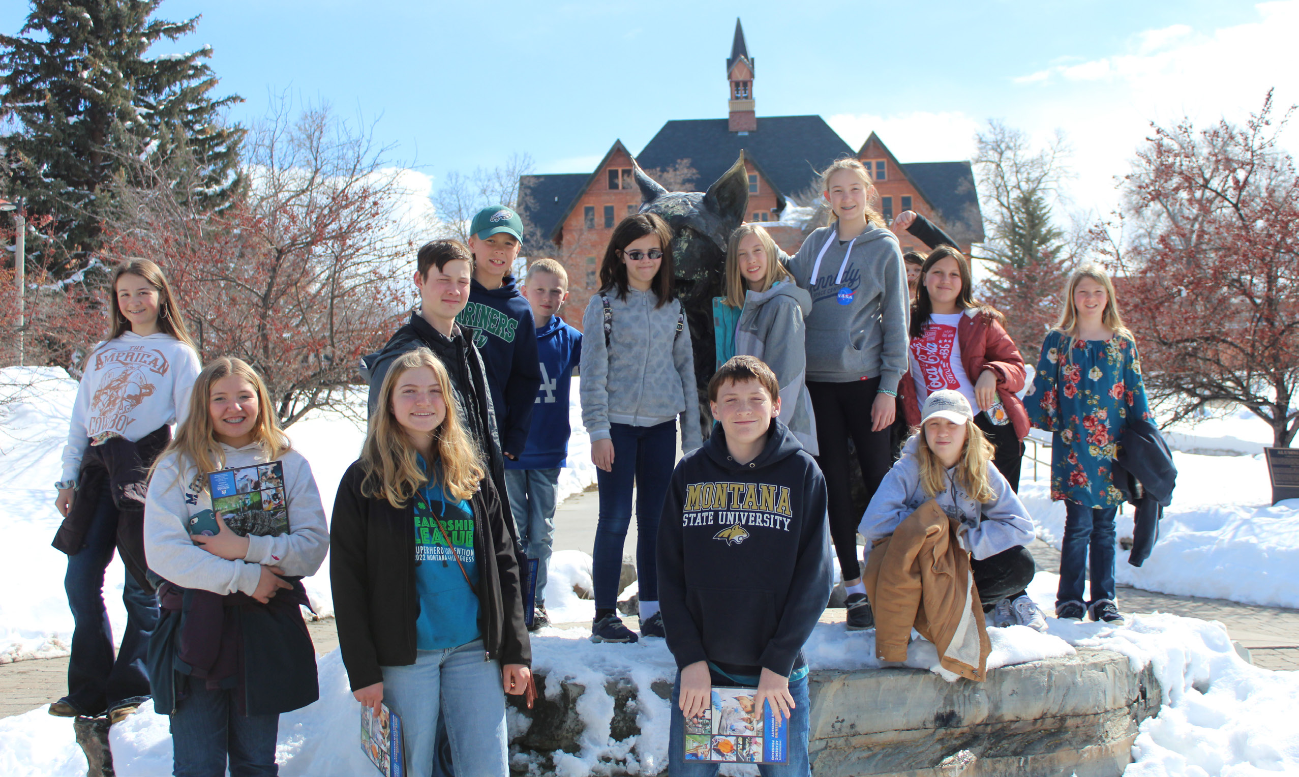 Group of 13 youth standing next to the Montana State University Spirit the Bobcat statue.