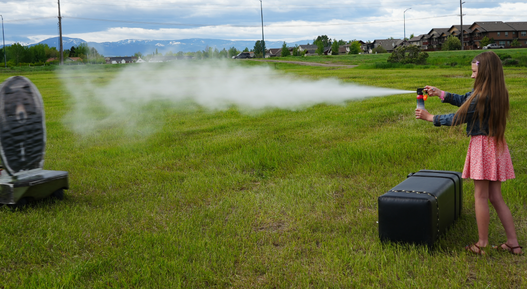 a young girl using bear spray on a blow up bear for practice