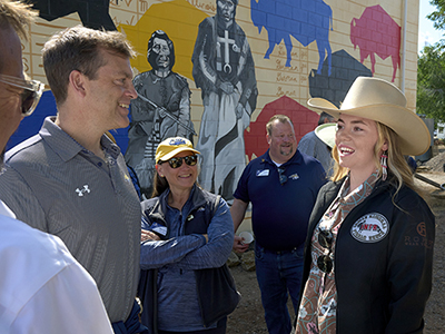 MSU Bus Tour Participants in a community event conversing near a mural.