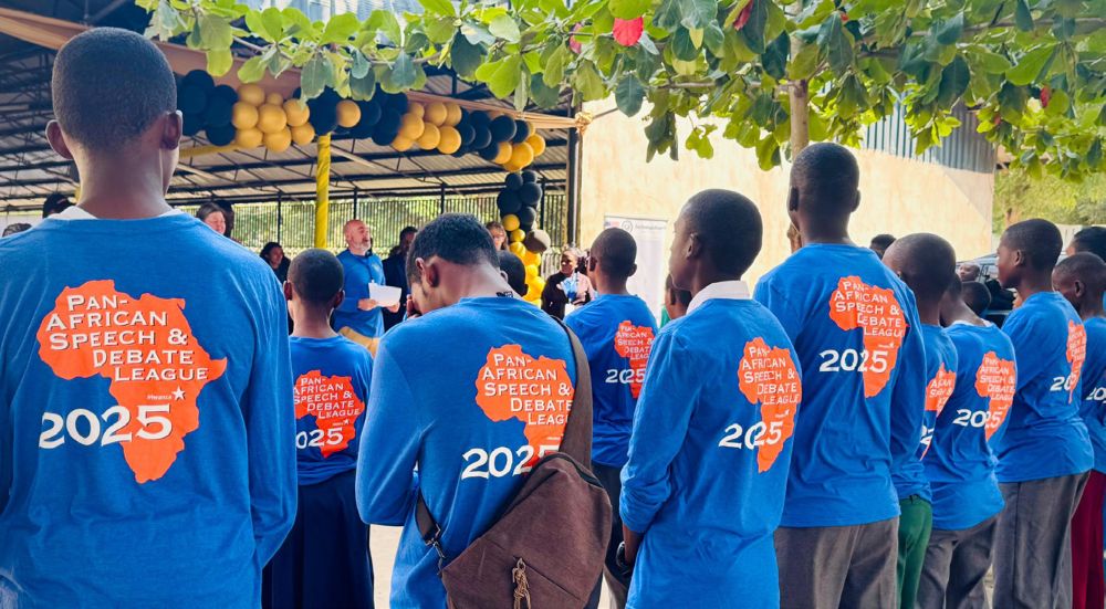 Participants wearing blue shirts with 'Pan-African Speech & Debate League 2025' printed on the back while attending an outdoor event.
