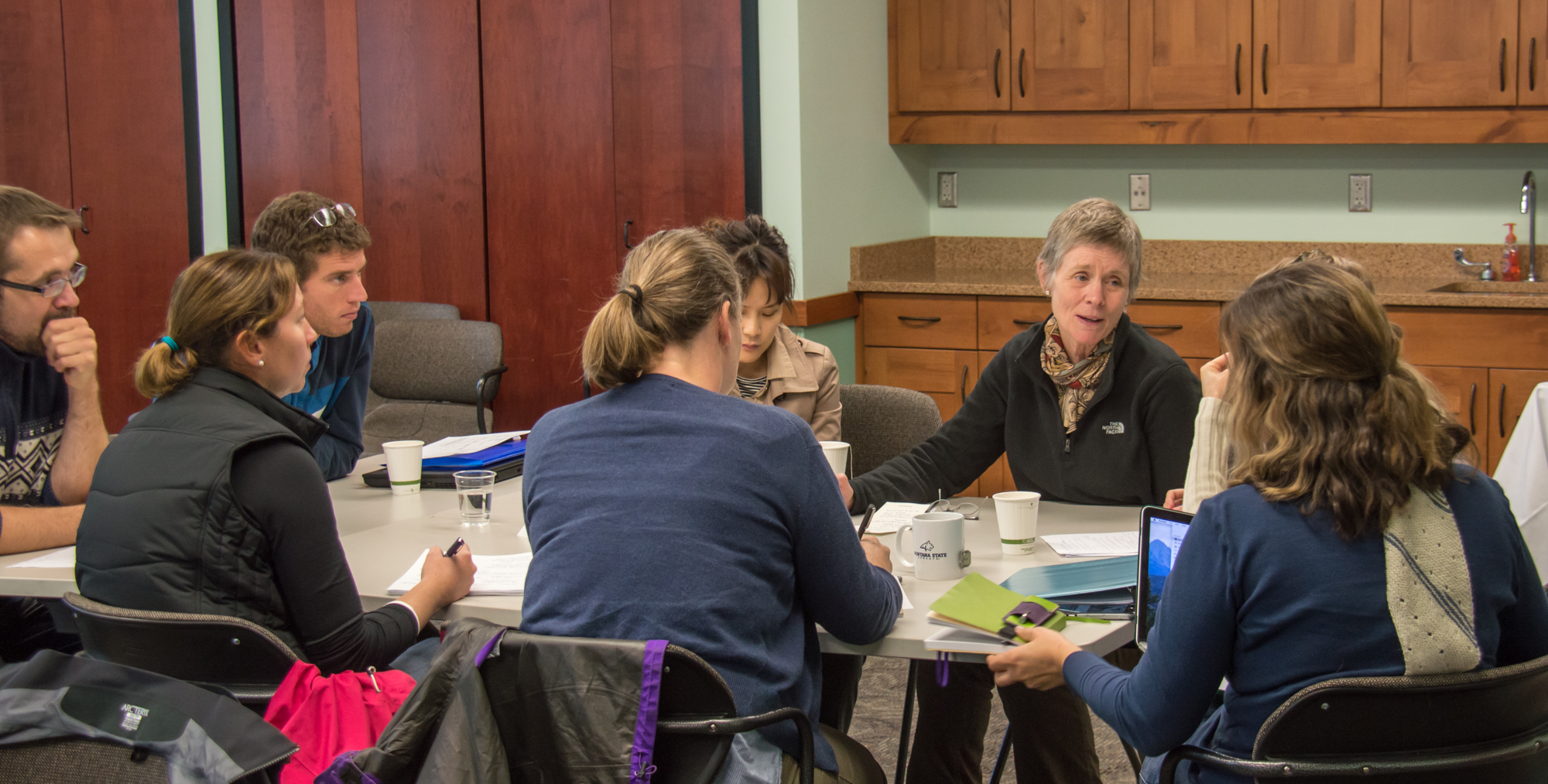 five people sitting around a meeting table
