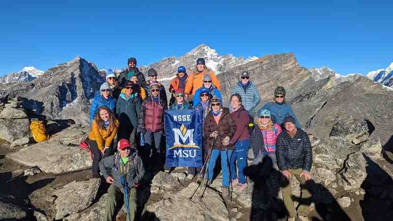 The group poses with the MSSE flag at the summit of Gokyo Ri