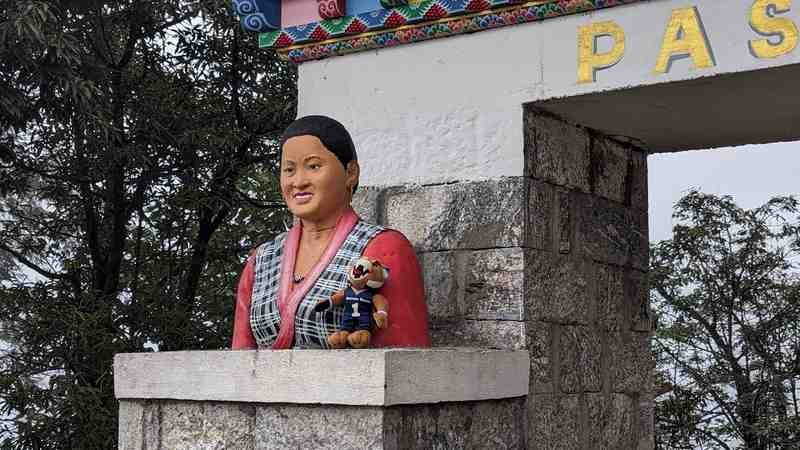 Champ the Bobcat poses next to a statue in Lukla