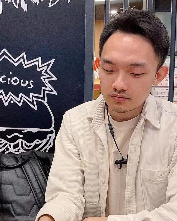 A person with short black hair wearing a white long sleeved button up shirt